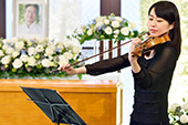花祭壇の前でヴァイオリンを弾く女性